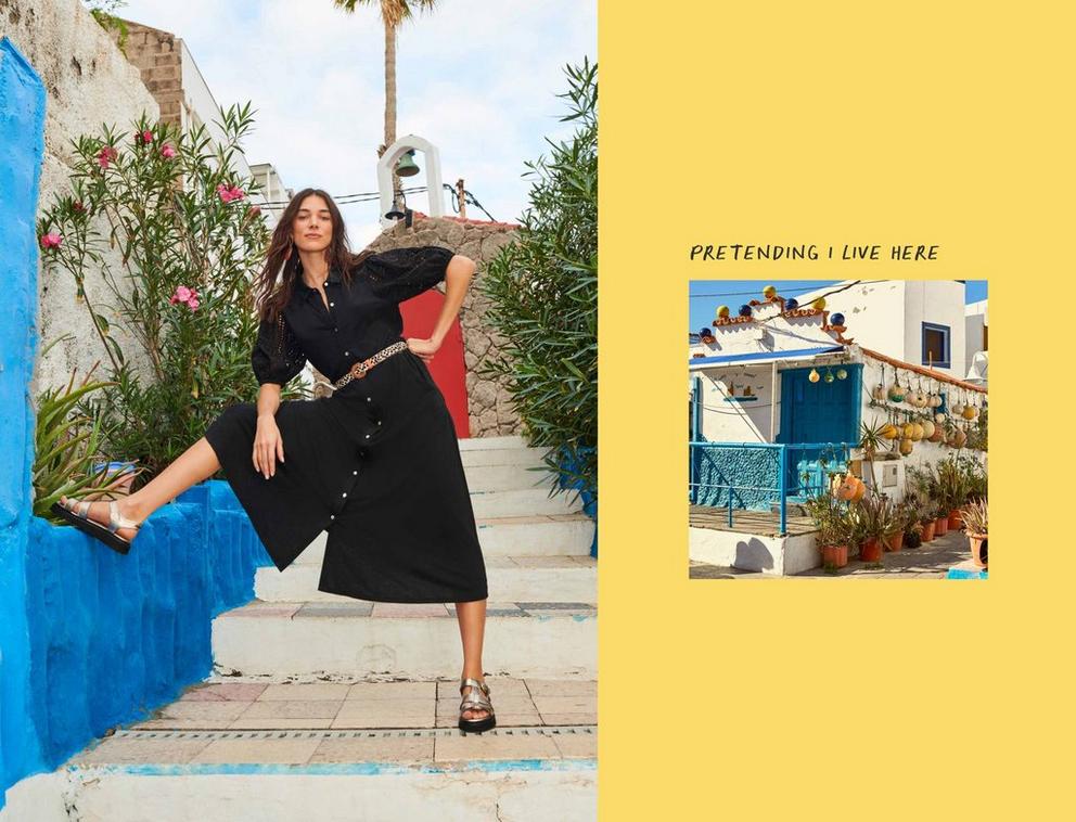 Woman in black linen dress with foot on blue wall